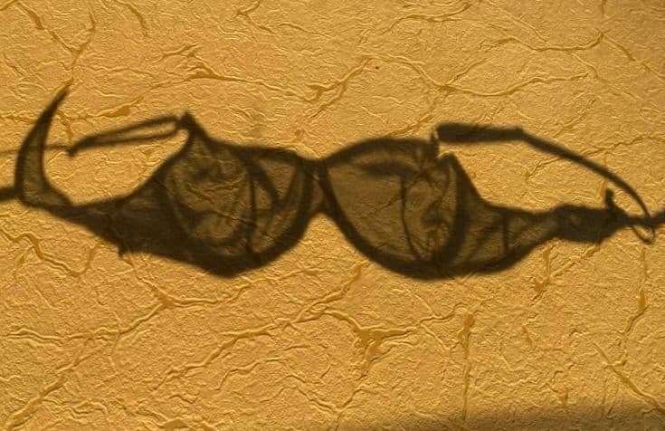 a woman holding her boobs wearing a bra and a blue jeans - Free the Nipples